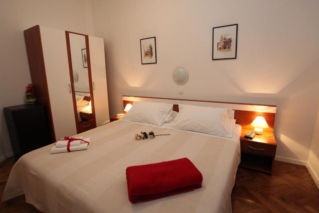 ein Schlafzimmer mit einem großen weißen Bett und einem roten Handtuch darauf in der Unterkunft Vincent apt. in old town centre in Zadar