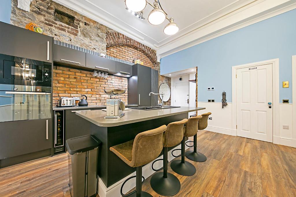 a kitchen with a bar with stools and a brick wall at Market Street Apartments ✪ Grampian Lettings Ltd in Aberdeen