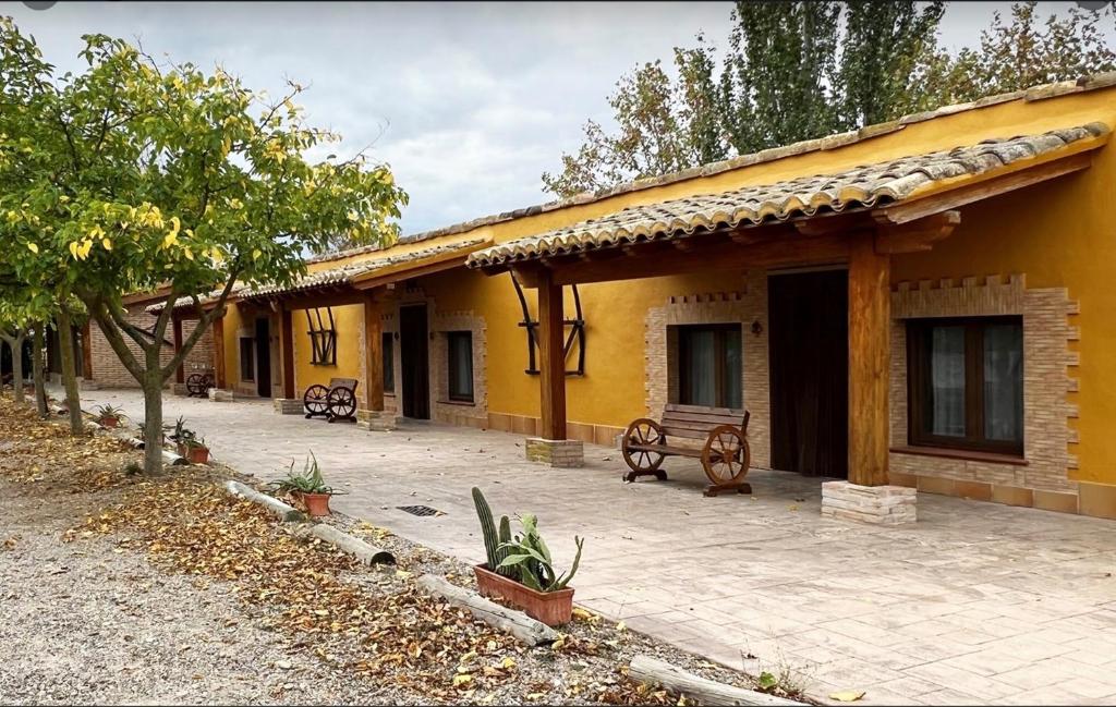een geel huis met een bankje ervoor bij Alojamiento Rural La Alberca in Arguedas