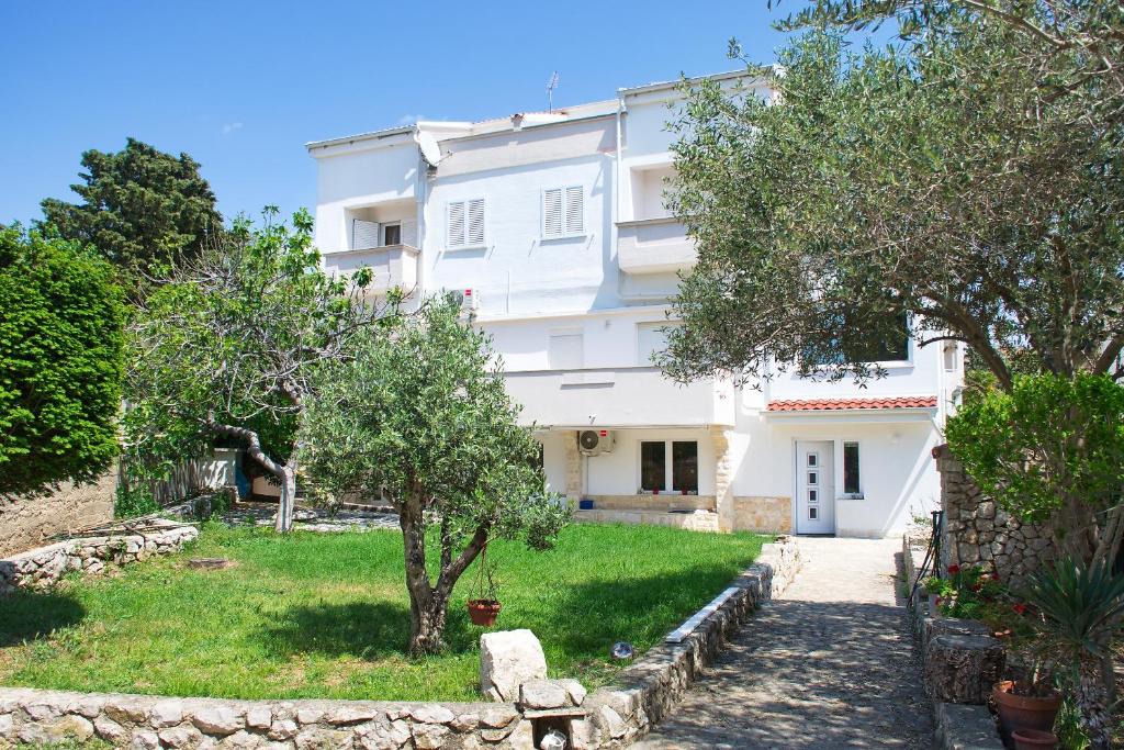 a white house with trees in front of it at Apartments Summer Joy in Novalja