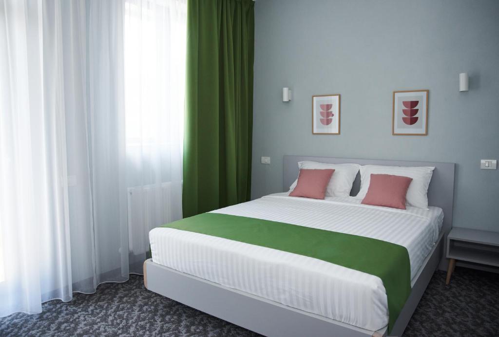 um quarto com uma cama grande e cortinas verdes em Astra Hotel em Călimăneşti