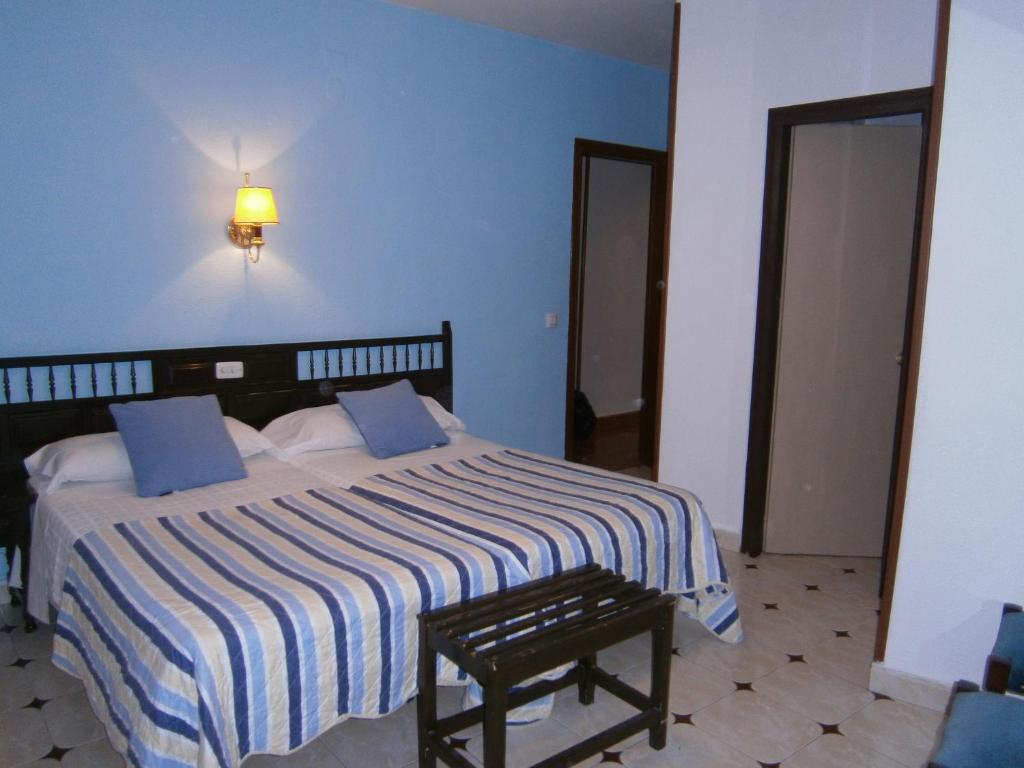 1 dormitorio con 1 cama grande y pared azul en Hostal Residencia Avenida en Cuenca