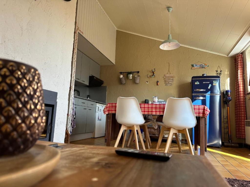 a kitchen with a table and three white chairs at Le petit Rabais in Virton