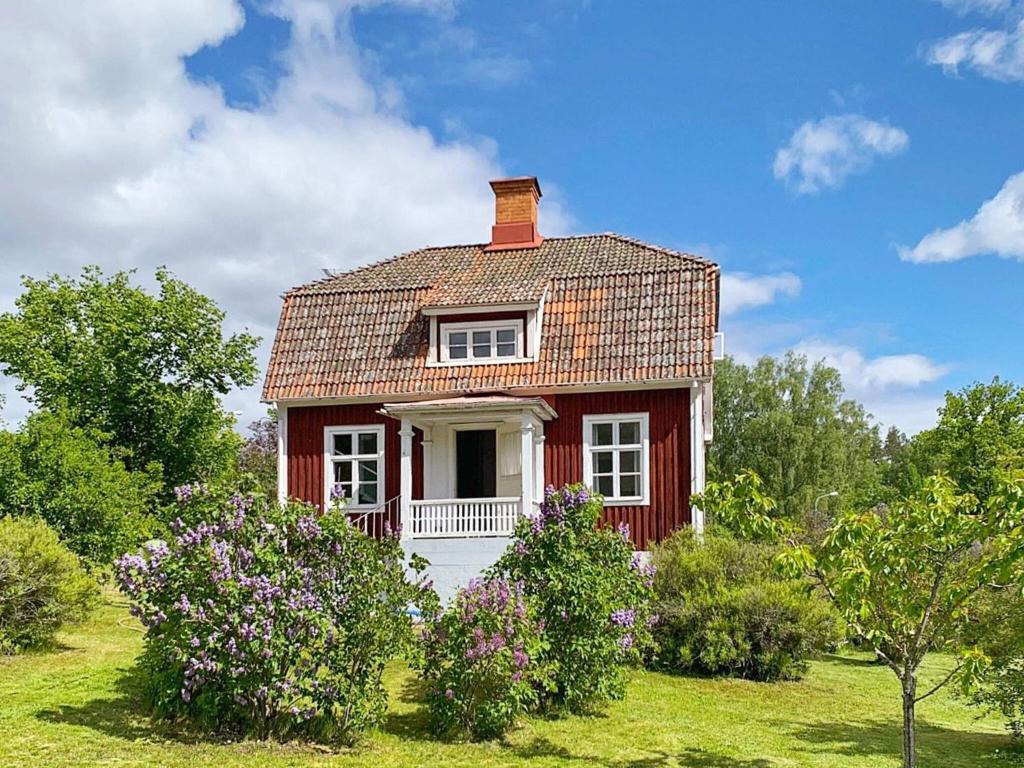 uma pequena casa vermelha num campo com flores em Holiday home Edsbruk em Edsbruk