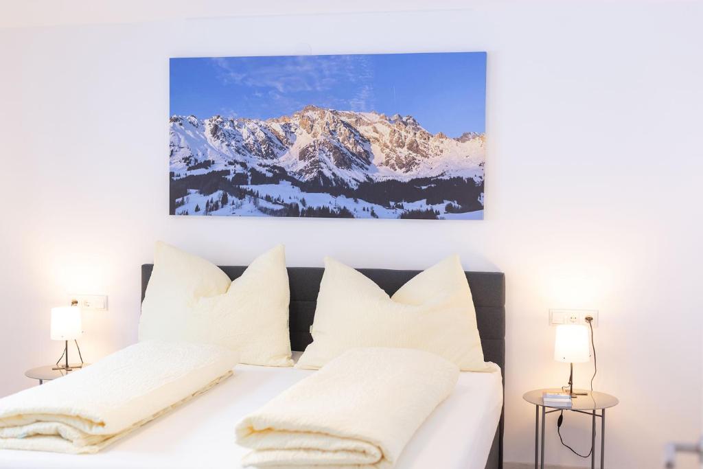 Un dormitorio con una cama blanca con montañas cubiertas de nieve en Der Hochkönigblick, en Dienten am Hochkönig