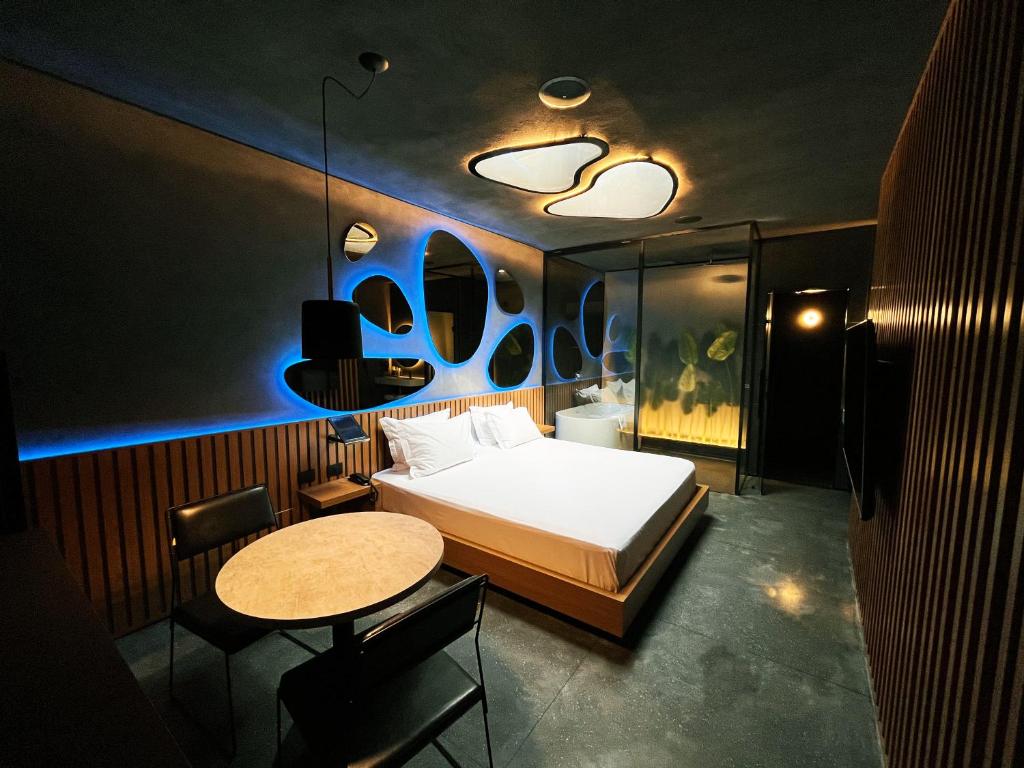 1 dormitorio con 1 cama, mesa y sillas en Lush Motel Lapa, en São Paulo