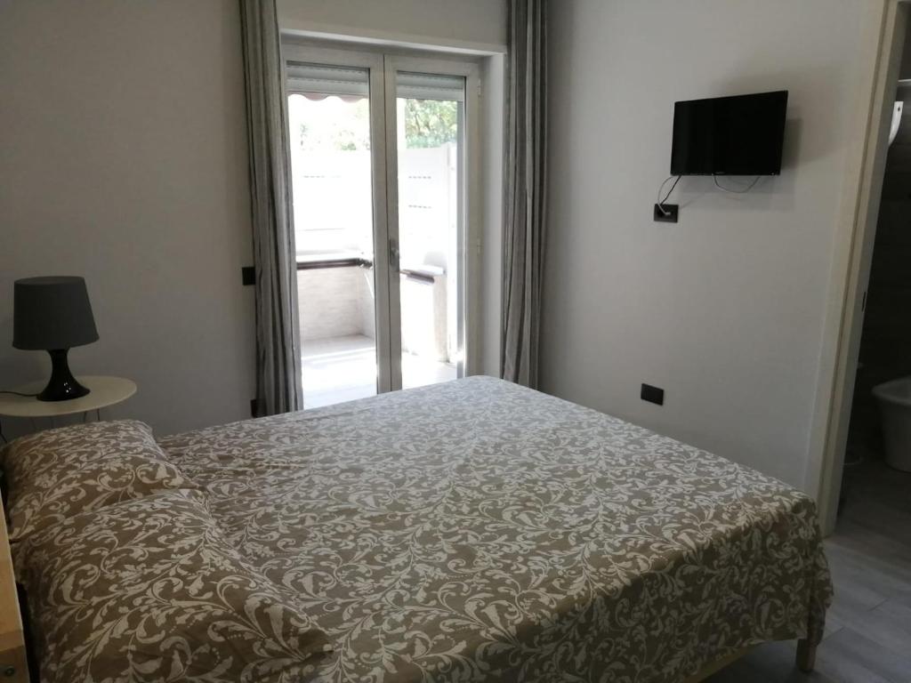 1 dormitorio con cama, ventana y TV en B&B San Pietro, en Scafati