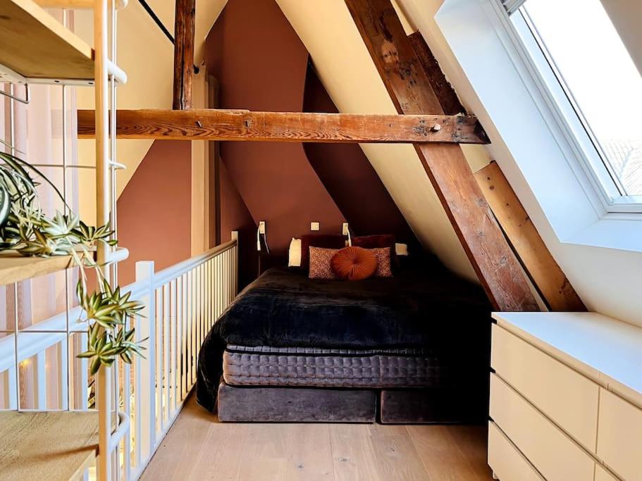 a attic room with a bed and a staircase at Gloria's loft op de Grote Markt in Breda