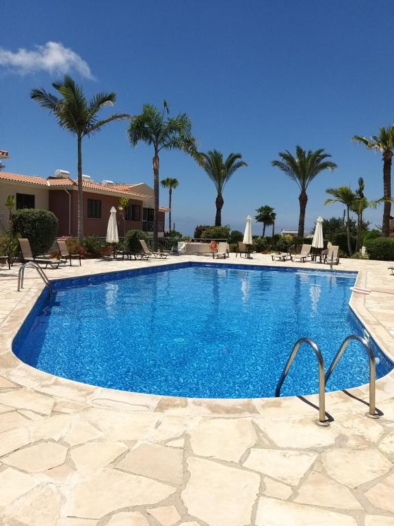 a swimming pool in a resort with palm trees at Tala Gardens Apartment in Tala