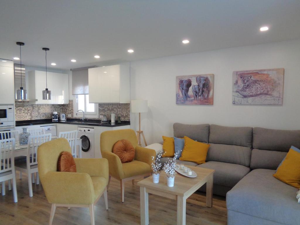 ein Wohnzimmer mit einem Sofa und Stühlen sowie eine Küche in der Unterkunft Villa MyRuedo in Fuengirola