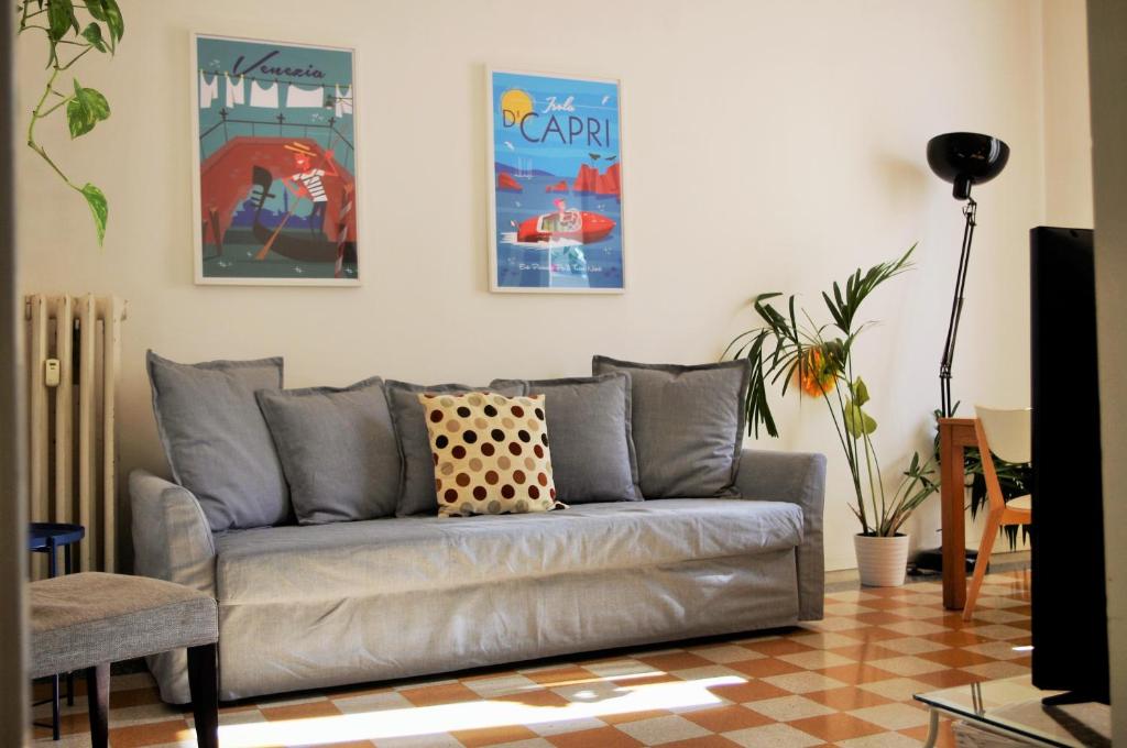 uma sala de estar com um sofá e cartazes na parede em Incantevole Appartamento De Angeli em Milão