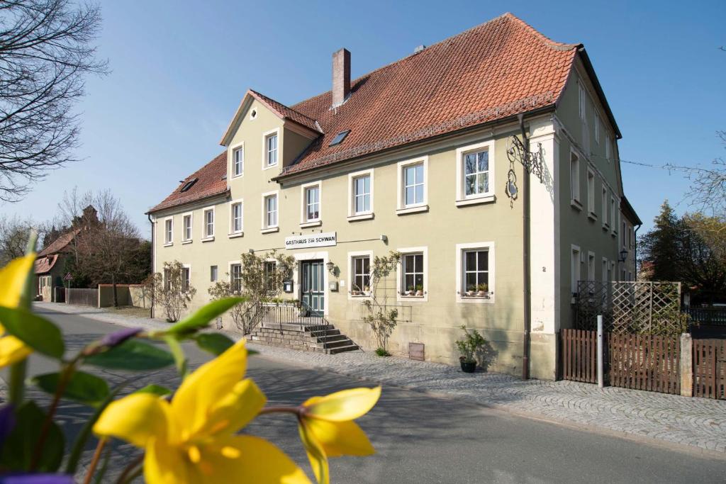 a yellow building with a red roof at Gasthaus zum Schwan in Castell