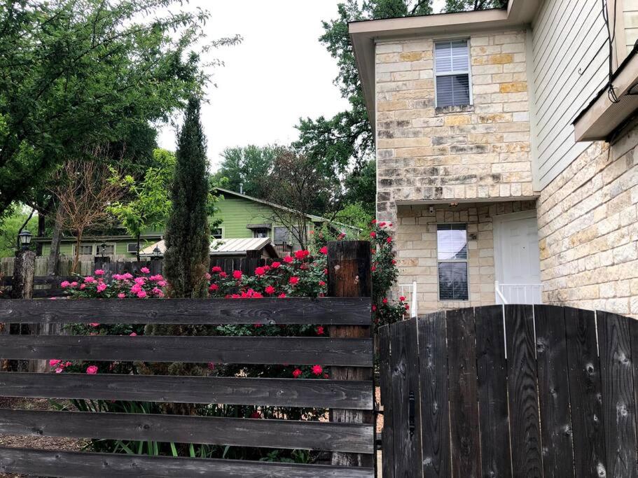 ein Holzzaun vor einem Haus mit Blumen in der Unterkunft Cozy 3-bed Garden Home - 10 mins to UT Stadium and Downtown Austin in Austin
