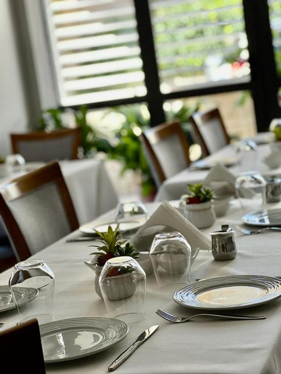 einen Tisch mit weißen Tellern und Gläsern darauf in der Unterkunft Hotel Mimani in Berat