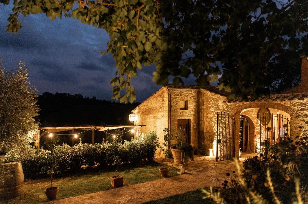 una vecchia casa in pietra di notte con luci di Podere La Paolina a Montefollonico
