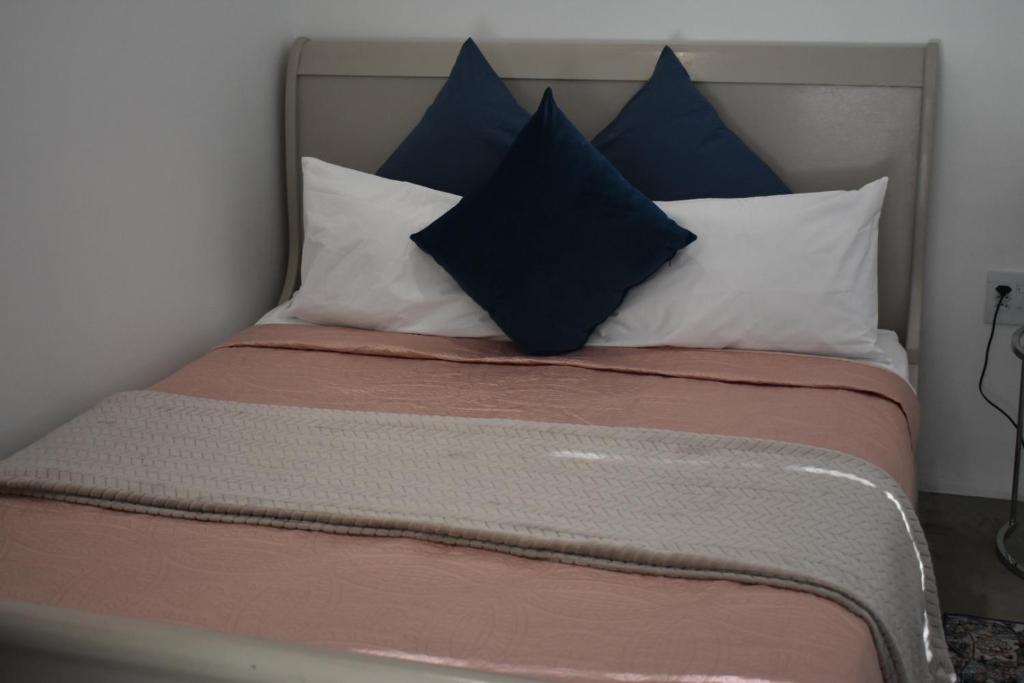 a bed with blue and white pillows on it at Langbeentjie Inn Two Point O in Cape Town