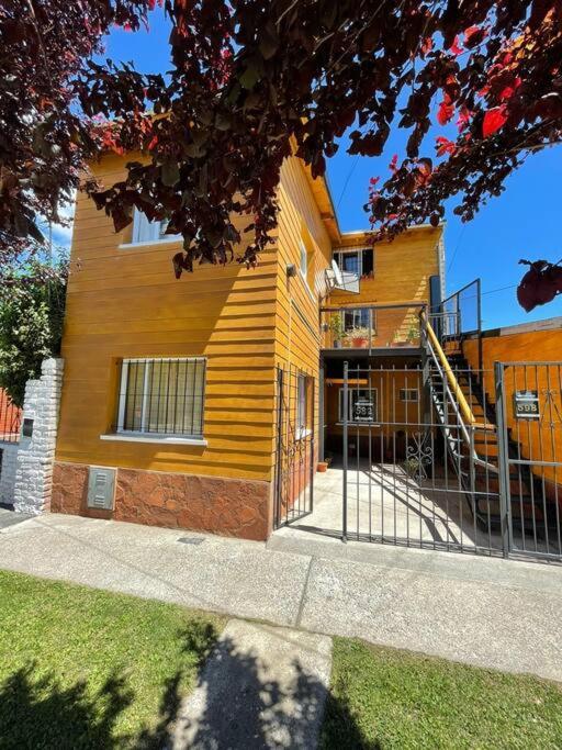 un edificio amarillo con escaleras a un lado en El Arrayan Departamento en Esquel