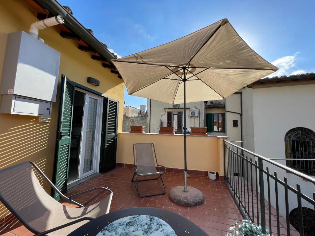 un patio con ombrellone e sedie su un balcone di Appartamento Firenze Centro Amorino con terrazzo a Firenze
