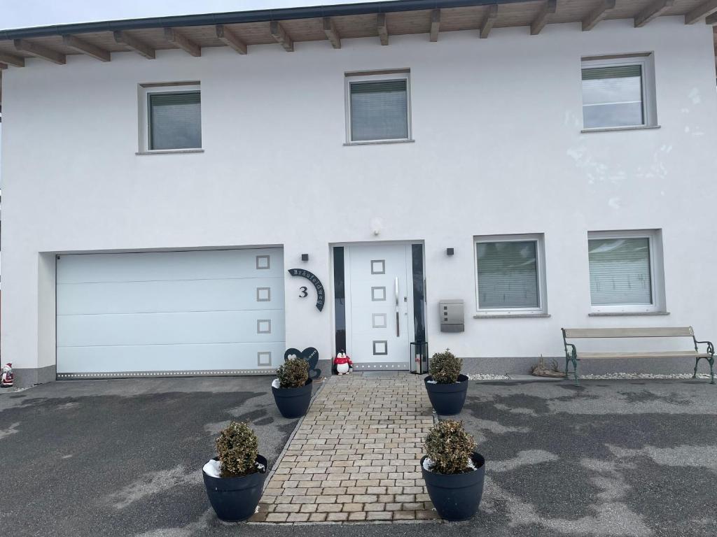 een wit huis met een garage met potplanten bij Karo`s Apartment in Mittersill