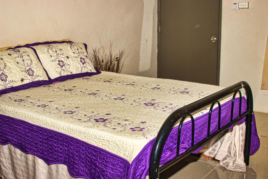 ein Bett mit lila und weißen Laken und Kissen in der Unterkunft Guddy’s Riverside Cottage in Nausori