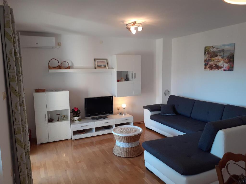 a living room with a blue couch and a tv at Apartman Bonaca in Jadranovo