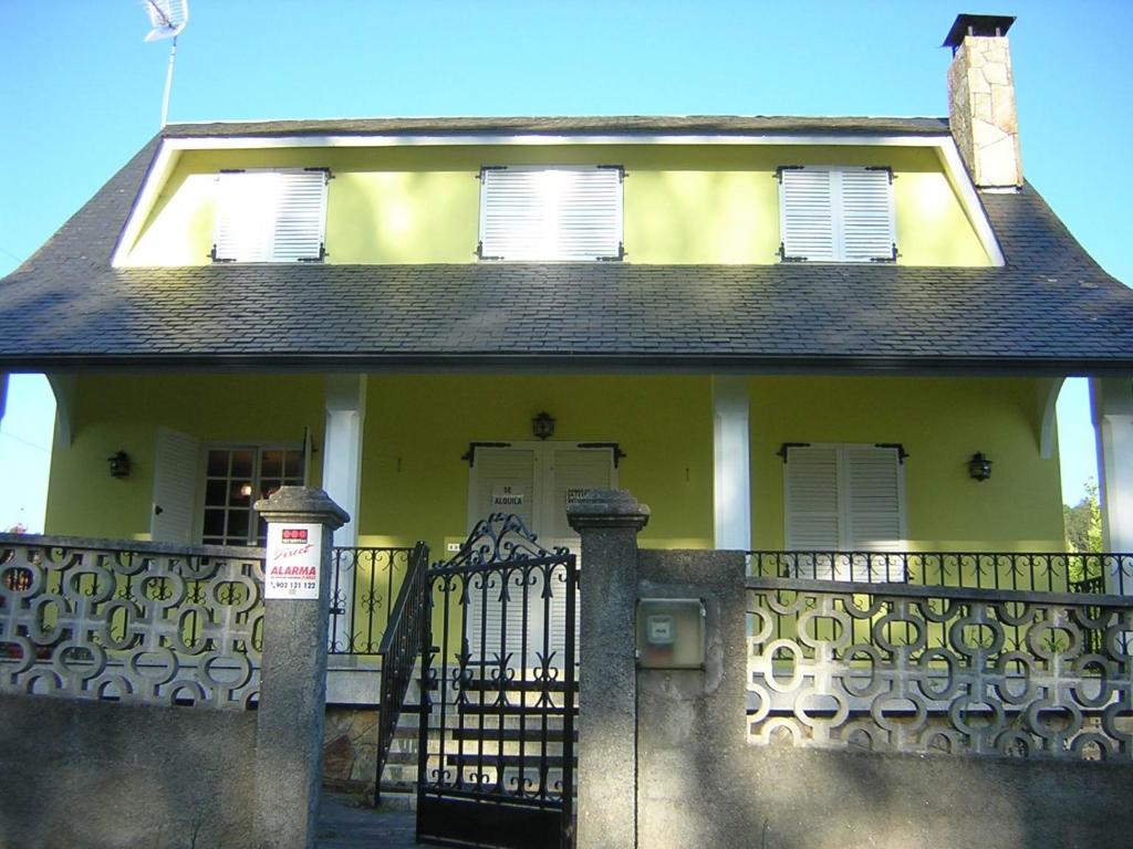 żółty dom z bramą i płotem w obiekcie Casa con jardín en la playa de Almieiras w mieście Fene