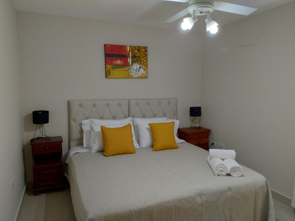 1 dormitorio con 1 cama blanca grande con almohadas amarillas en Independencia 880 Nueva Córdoba 2 hab 2 baños 2 a 5pax en Córdoba