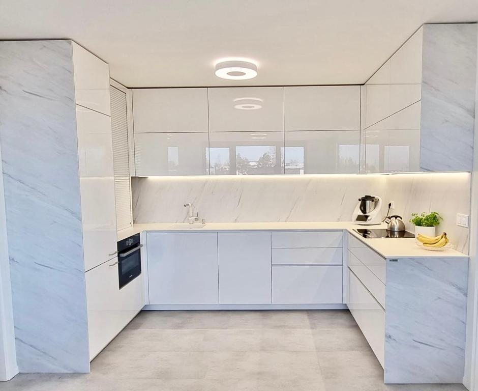 una cocina blanca con armarios blancos y fregadero en Luxury Penthouse Apartment, en Žďár nad Sázavou