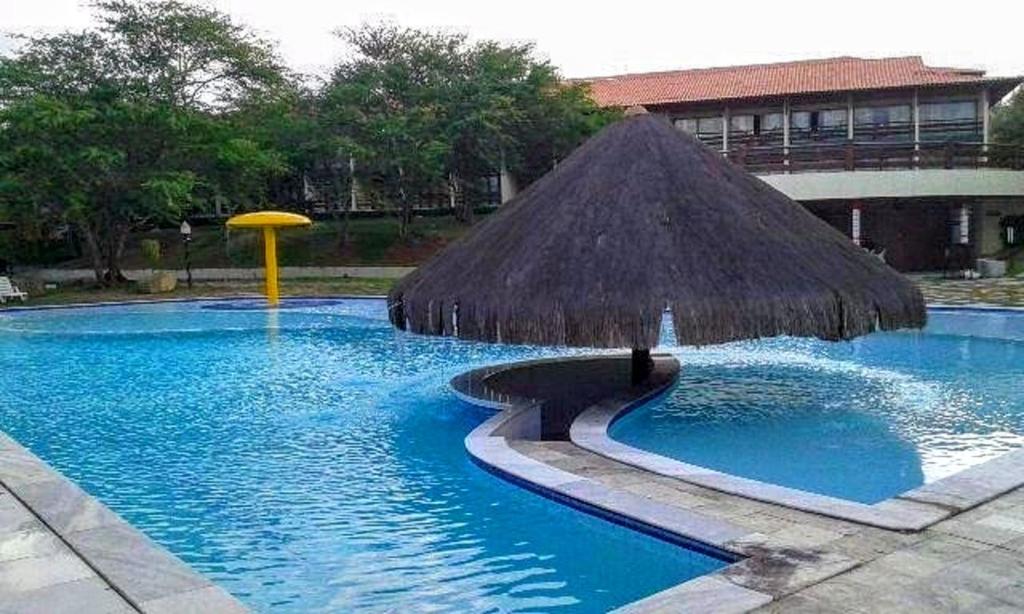 - une piscine avec un parasol dans l'établissement Flat 2A Hotel Monte Castelo Gravatá 2 quartos, à Bezerros