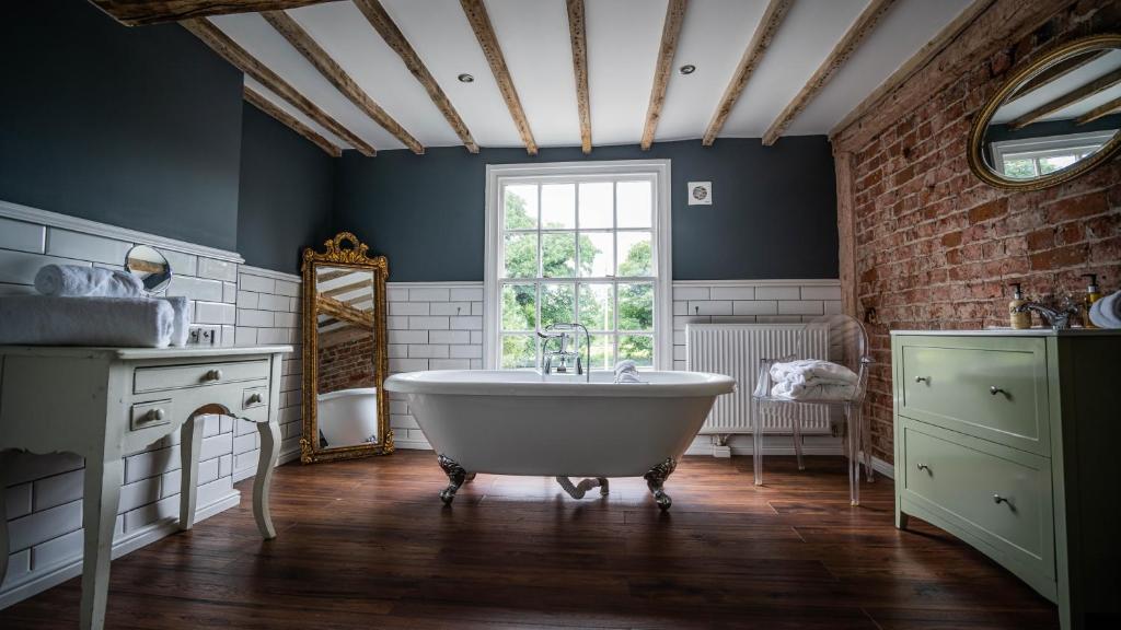 ein Bad mit einer weißen Badewanne und einem Fenster in der Unterkunft The Vicarage in Holmes Chapel