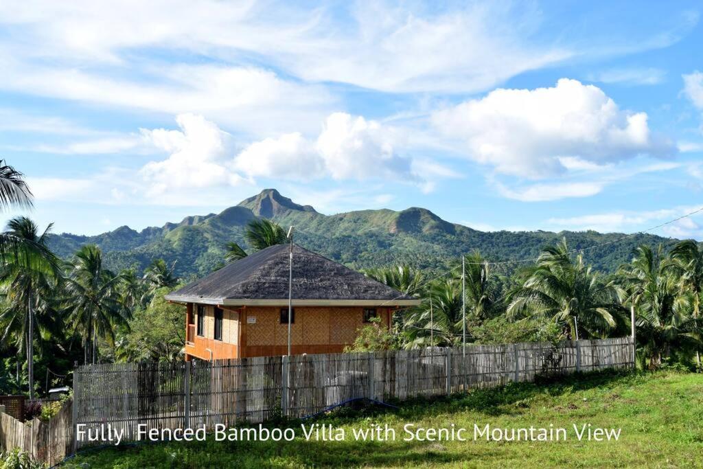 une maison avec une clôture et des montagnes en arrière-plan dans l'établissement Luxury Bahay Kubo in a Farm Near Tagaytay, à Tagaytay