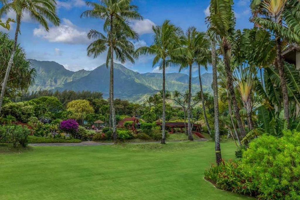 a lawn with palm trees and mountains in the background at Hanalei Bay Resort BaliHi in Princeville