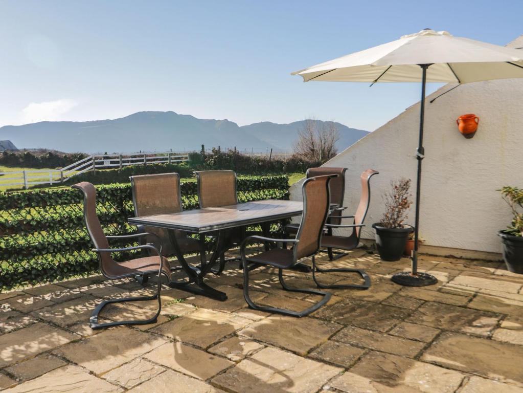 een patio met een tafel en stoelen en een parasol bij Beach House Ty Traeth in Deganwy