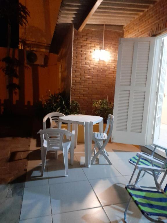 une table blanche et des chaises assises sur une terrasse dans l'établissement Casa Moita, Linda Casa, Muito Central, Hospeda até 9 ou 12 Pessoas, à Rio Grande