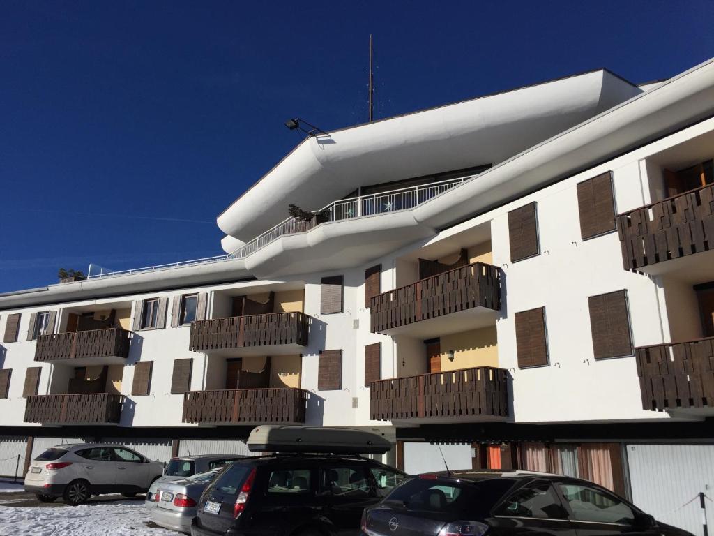 un edificio blanco con coches estacionados en un estacionamiento en Camera Alpe di Siusi, en Alpe di Siusi