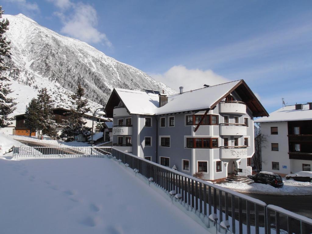 a building in the snow with a mountain in the background at Haus Dorfplatz in Galtür
