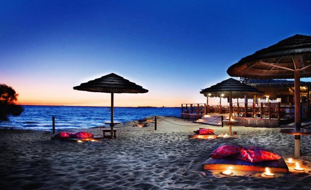 una playa con sombrillas y el océano por la noche en B&B Anxa, en Gallipoli