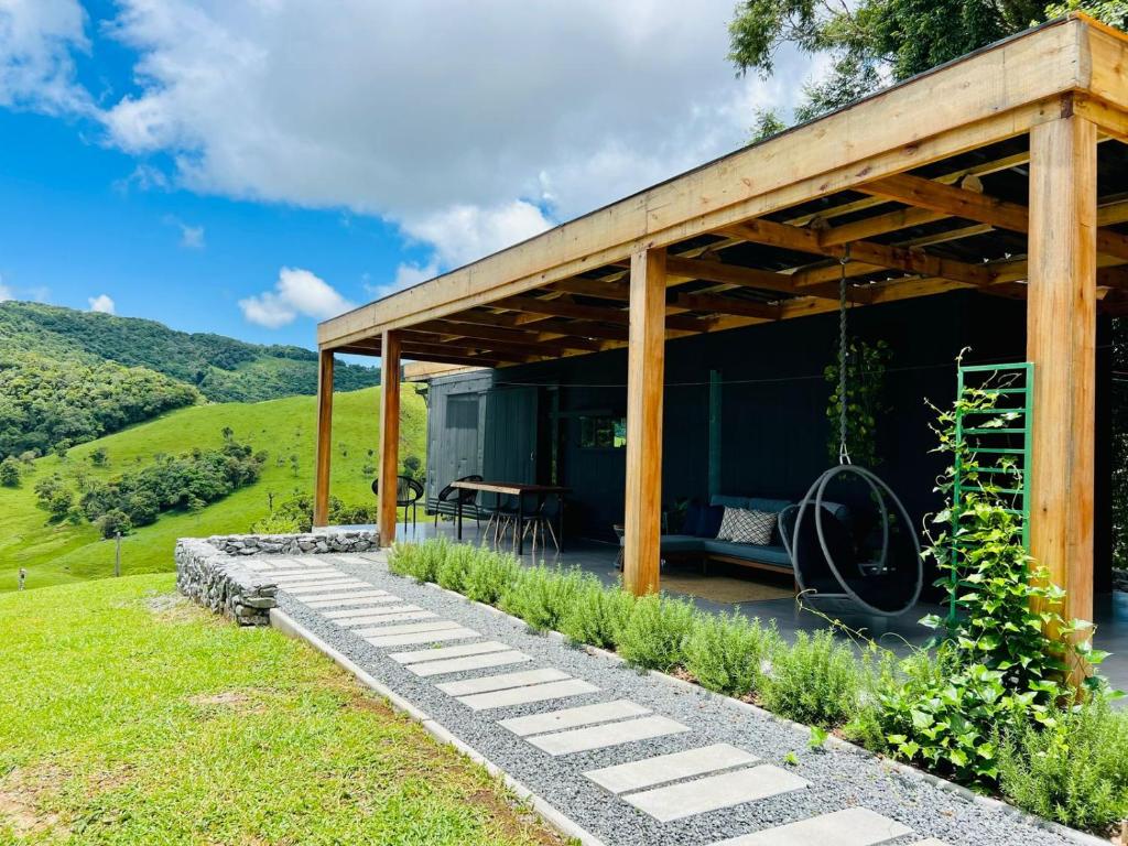 uma casa verde com um telhado de madeira e um baloiço em Cabana Romântica na Região dos Lagos em Rio dos Cedros