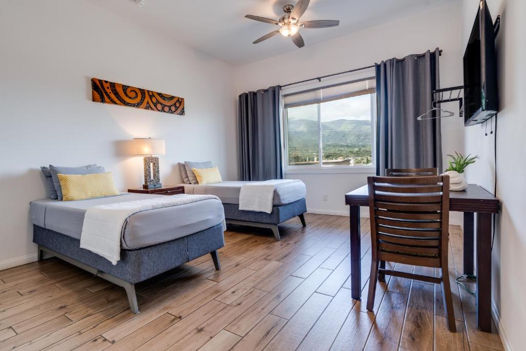 a bedroom with two beds and a desk and a window at Unit 5 Maui Ohana Modern Studio in Wailuku