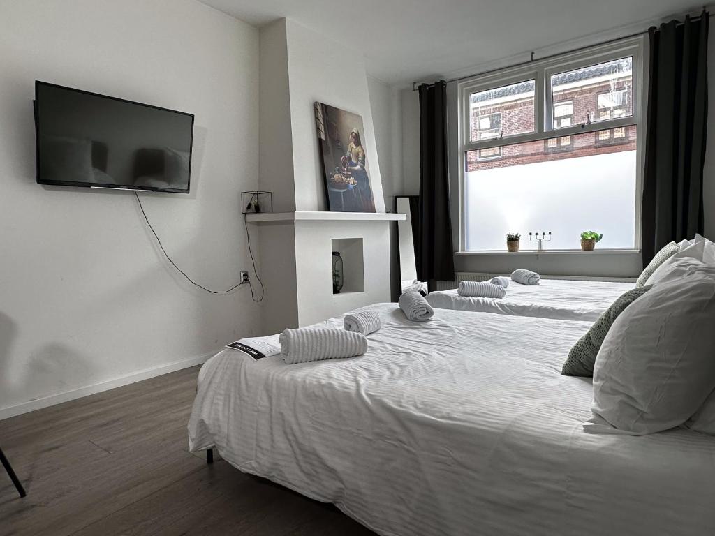 a bedroom with a white bed with a tv on the wall at Hidden Gem next to TU Delft Campus Family XL house in Delft