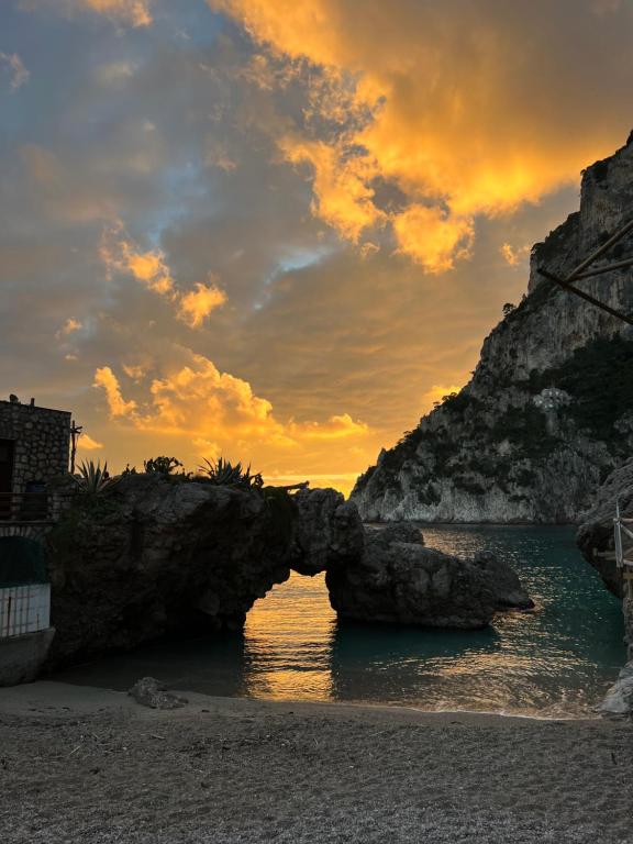 an arch in the water on a beach at sunset at Capri room on the beach in Capri