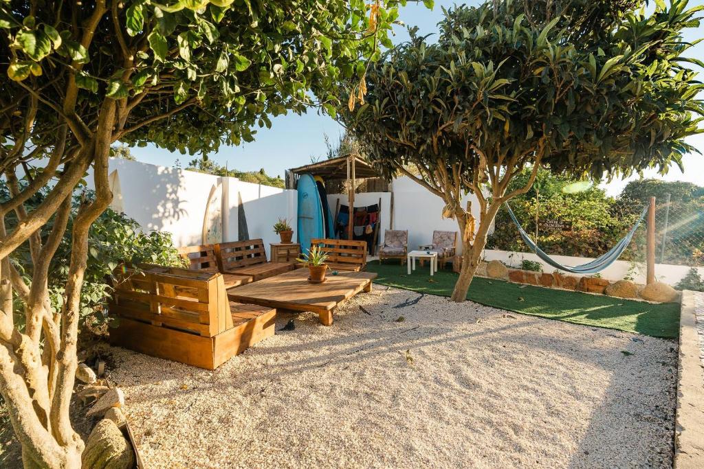 a patio with a hammock and two trees at Aldeia Caiçara Surf House in Sagres