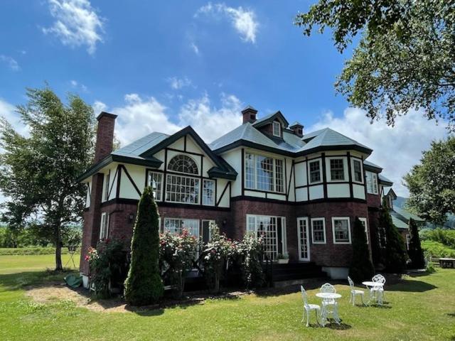 a large house on a lawn with chairs in front of it at Agri In Holiday in Hirosaki
