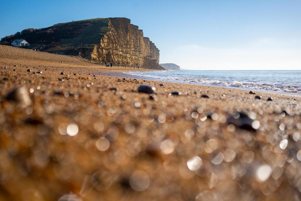 a beach with rocks and the ocean and a cliff at Bridport Arms Hotel in West Bay