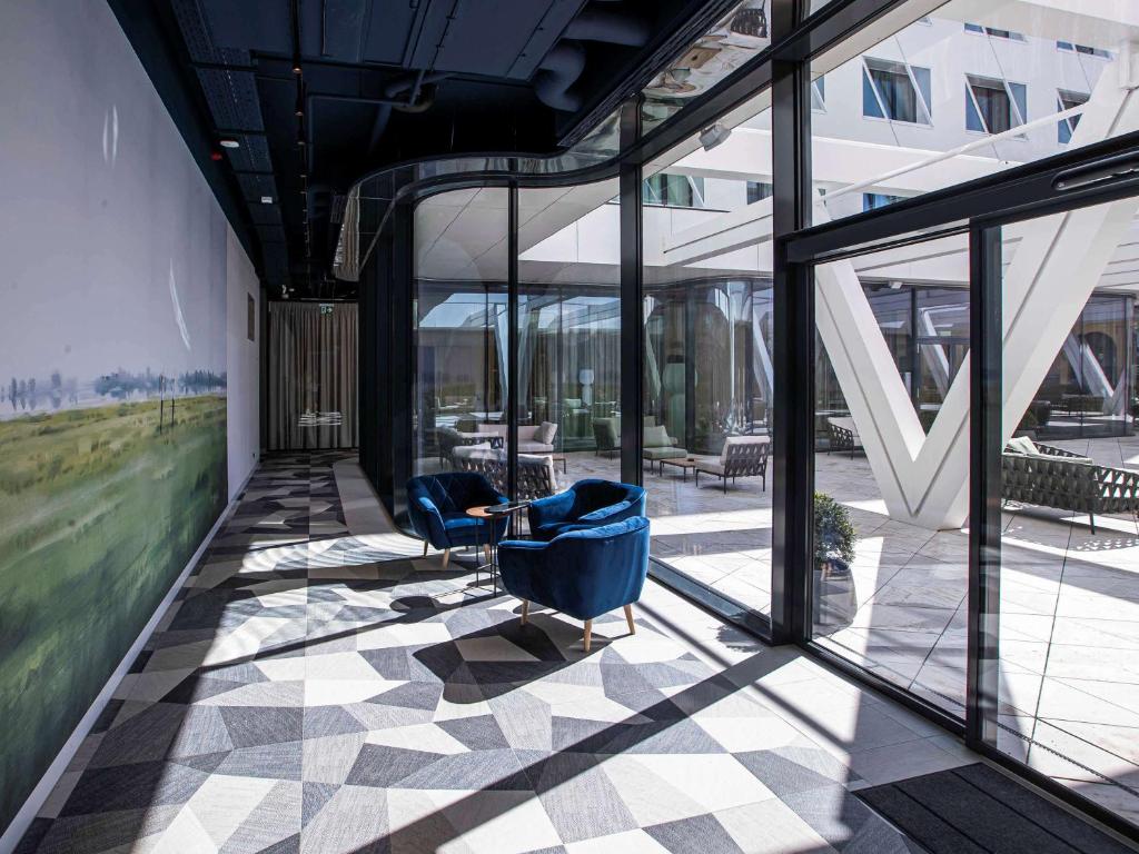 a lobby with two blue chairs and windows at Mercure Debrecen in Debrecen