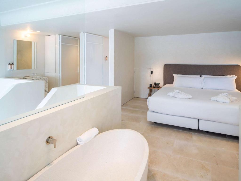 a white bathroom with a tub and a bed and a bath tub at Mercure Benidorm in Benidorm