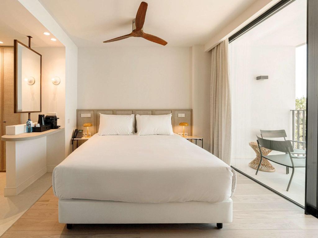 a bedroom with a white bed and a balcony at Mercure Benidorm in Benidorm