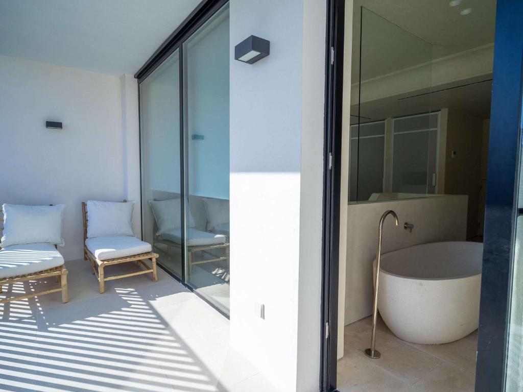 a bathroom with a tub and a chair next to a window at Mercure Benidorm in Benidorm