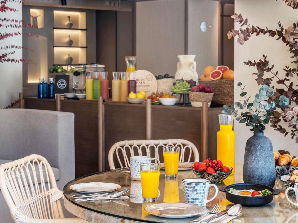 a table with chairs and a table with orange juice at Mercure Benidorm in Benidorm