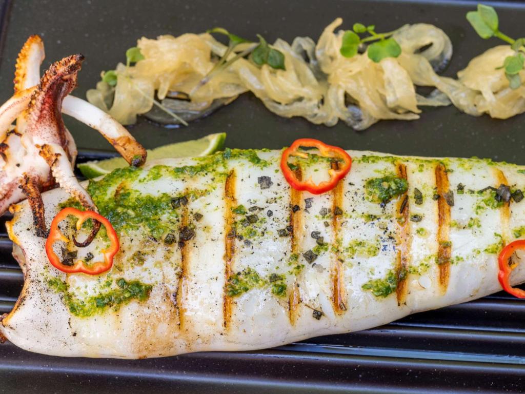 a piece of fish with red peppers on a black plate at Mercure Benidorm in Benidorm